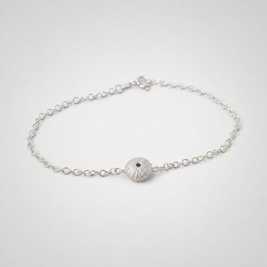Sterling Silver Sea Urchin Bracelet - flat lay on coastal rock texture