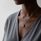 Handmade Brass Cowrie Shell Pendant - hanging view on grey gradient background