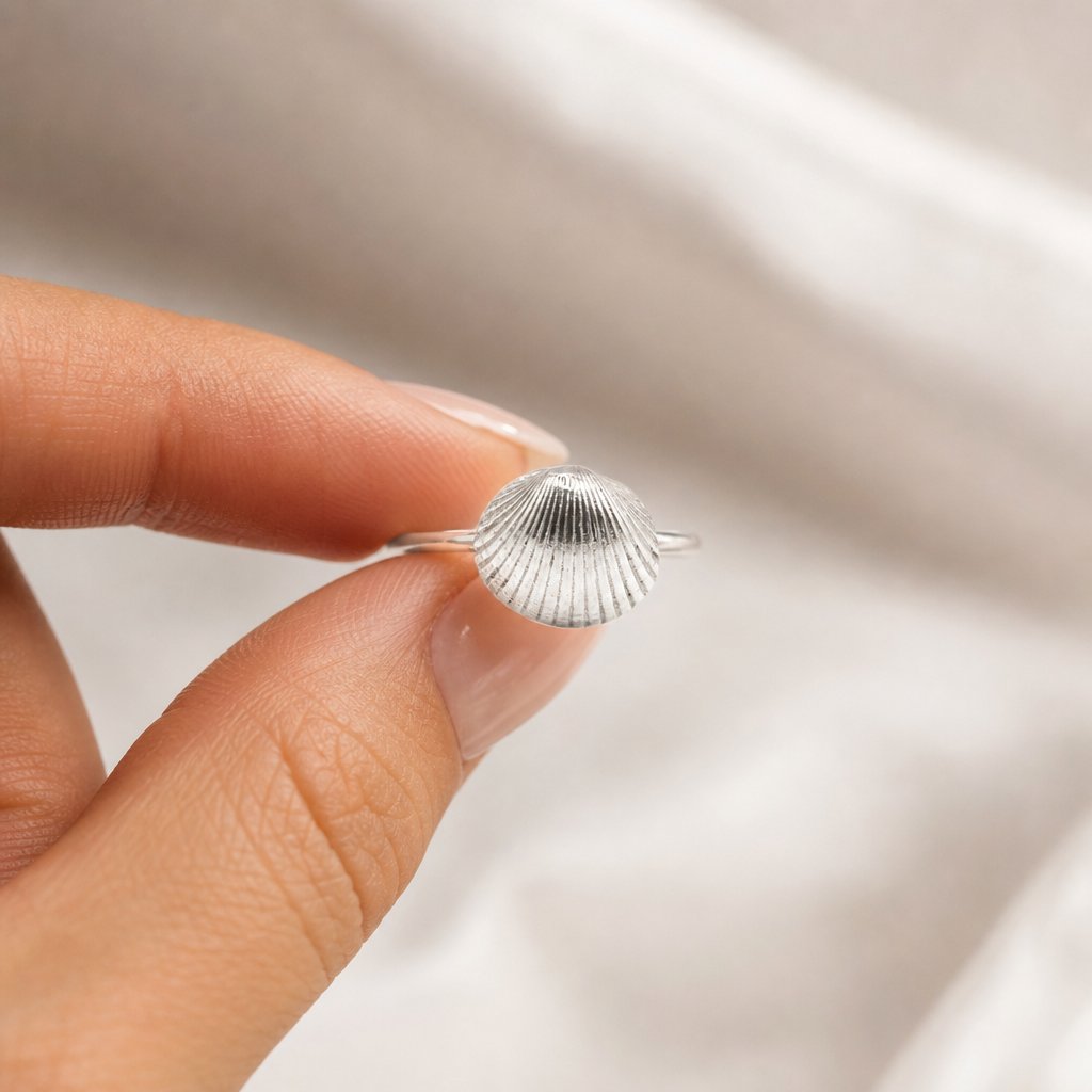 silver  Scallop Shell Ring - held between two fingers 