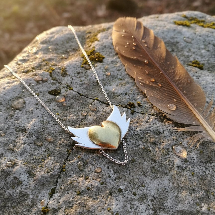 Brass Heart with Silver Wings Necklace - hero flat lay, mixed metal pendant on white background