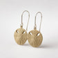 Small Pansy Shell Drop Earrings - brass variant front view on earring stand