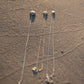 Small Sea Urchin Necklace - three sterling silver sea urchin pendants arranged on dark wet sand