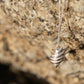 Tulip Conch Necklace - sterling silver pendant hanging against granite rock lifestyle shot