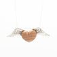 A delicate necklace featuring a heart-shaped olive wood pendant, accented by silver wings on either side. The smooth wooden heart contrasts beautifully with the finely detailed wings, all suspended on a slender silver chain.