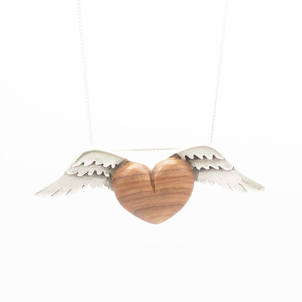 A delicate necklace featuring a heart-shaped olive wood pendant, accented by silver wings on either side. The smooth wooden heart contrasts beautifully with the finely detailed wings, all suspended on a slender silver chain.