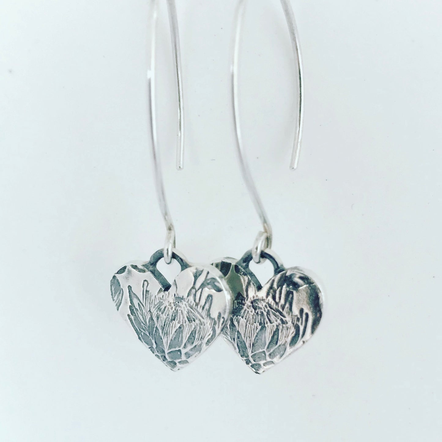 Zoomed-in view of large Protea Heart sterling silver earrings, highlighting the detailed craftsmanship.