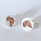 Close-up of handcrafted silver cufflinks with African continent cutout revealing olive wood detail.